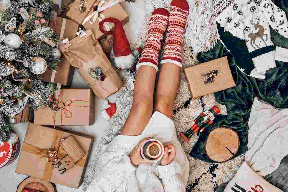 Natale, donna seduta tra regali e decorazioni per la casa