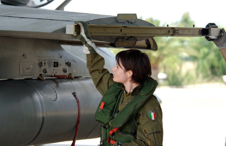 Samantha Cristoforetti che tocca un aereo dell'Areonautica Militare con una tuta delle Forze Armate italiane