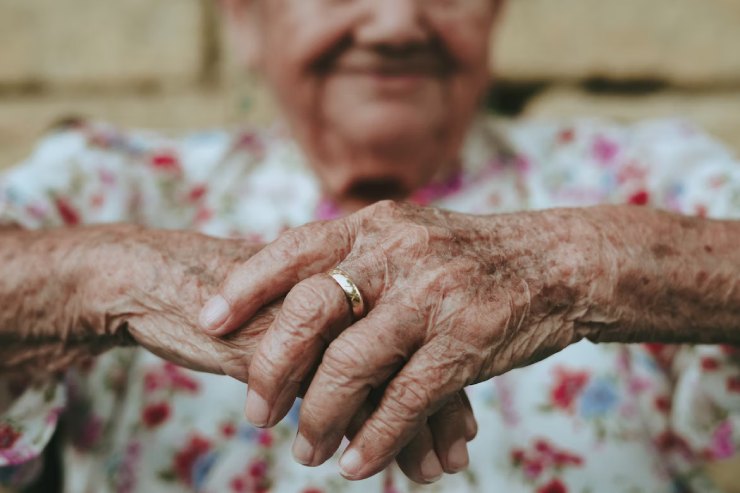 Mani di una donna anziana incrociate con anello