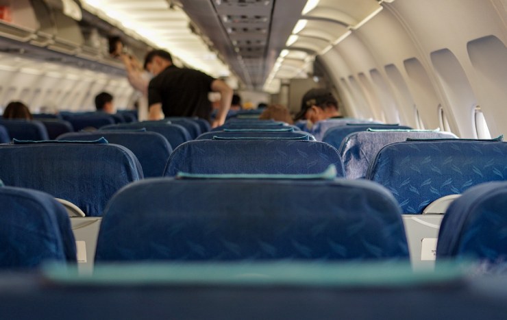 Interno di un aereo con sedili e persone in piedi