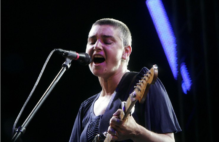 Sinead O Connor che canta con una chitarra in mano verso i suoi 30 anni