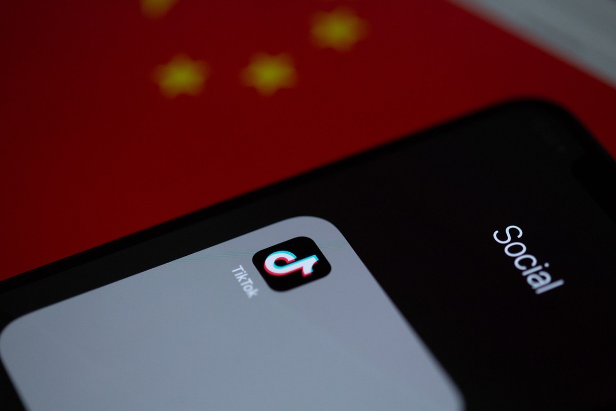 App di TikTok che si vede da un telefono e come sfondo la bandiera cinese rossa con stelle gialle