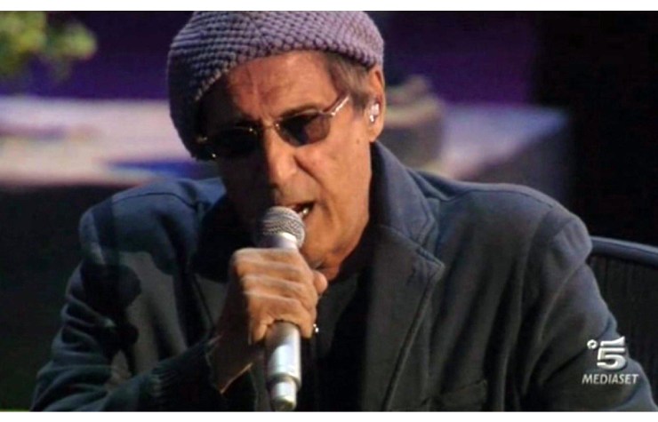 Adriano Celentano che canta con un berretto, occhiali e microfono