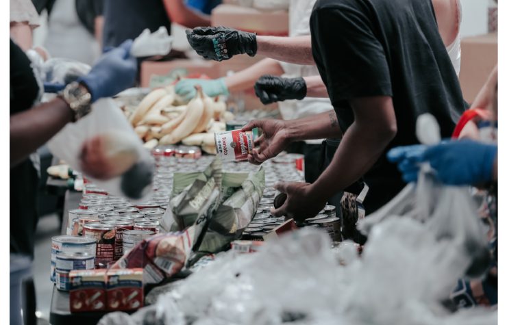 Persone che si scambiano cose sopra ad una bancarella con bene alimentari