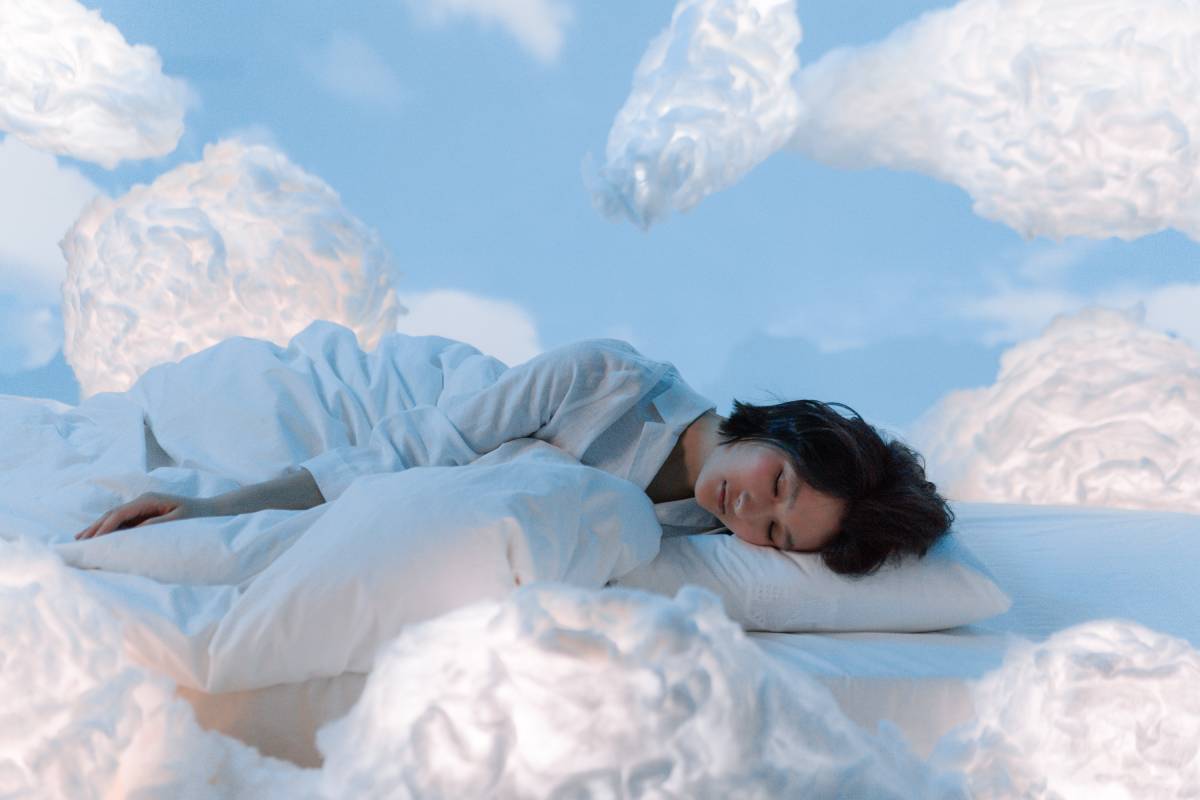 Ragazza che dorme su un letto di nuvole bianche e sogna
